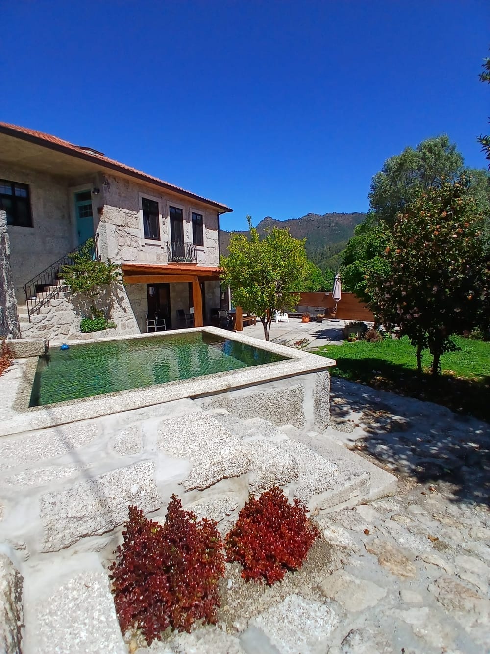 A casa e o tanque, com a serra ao fundo.