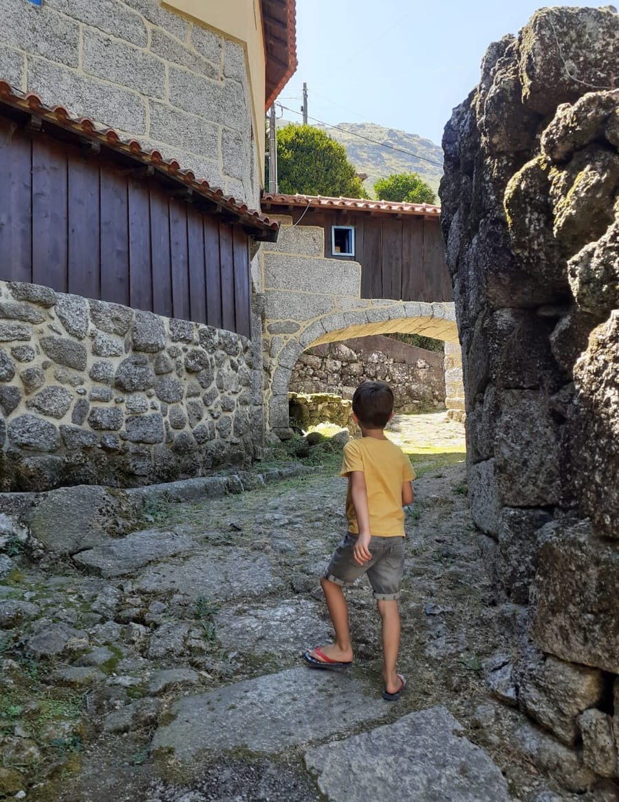 Uma viela em granito junto a casa, com o arco de pedra ao fundo.