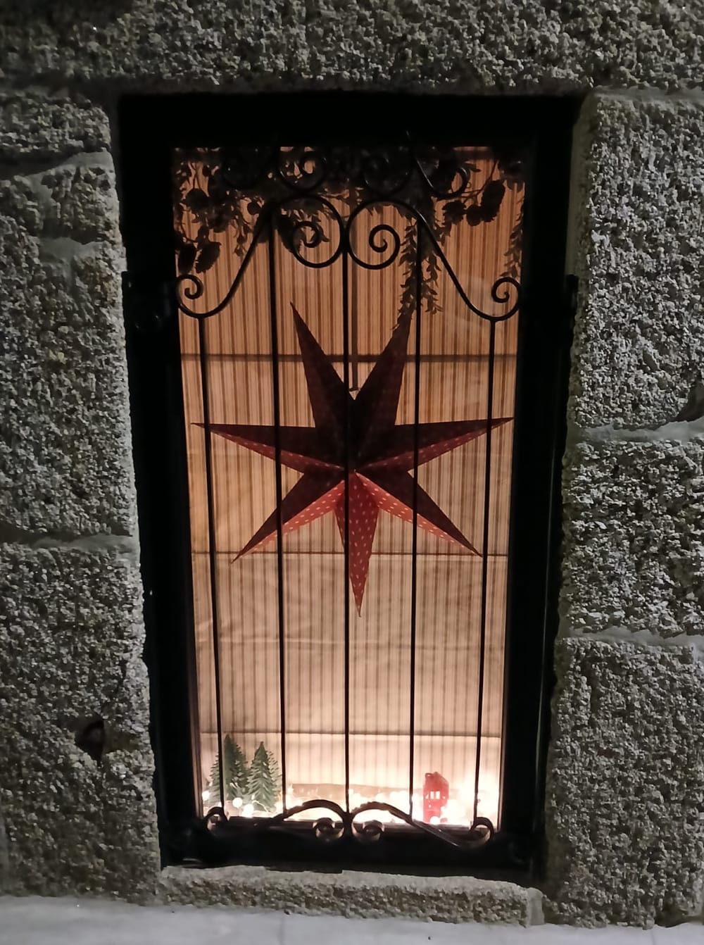 A janela de granito iluminada, com uma estrela em ferro, no Natal.