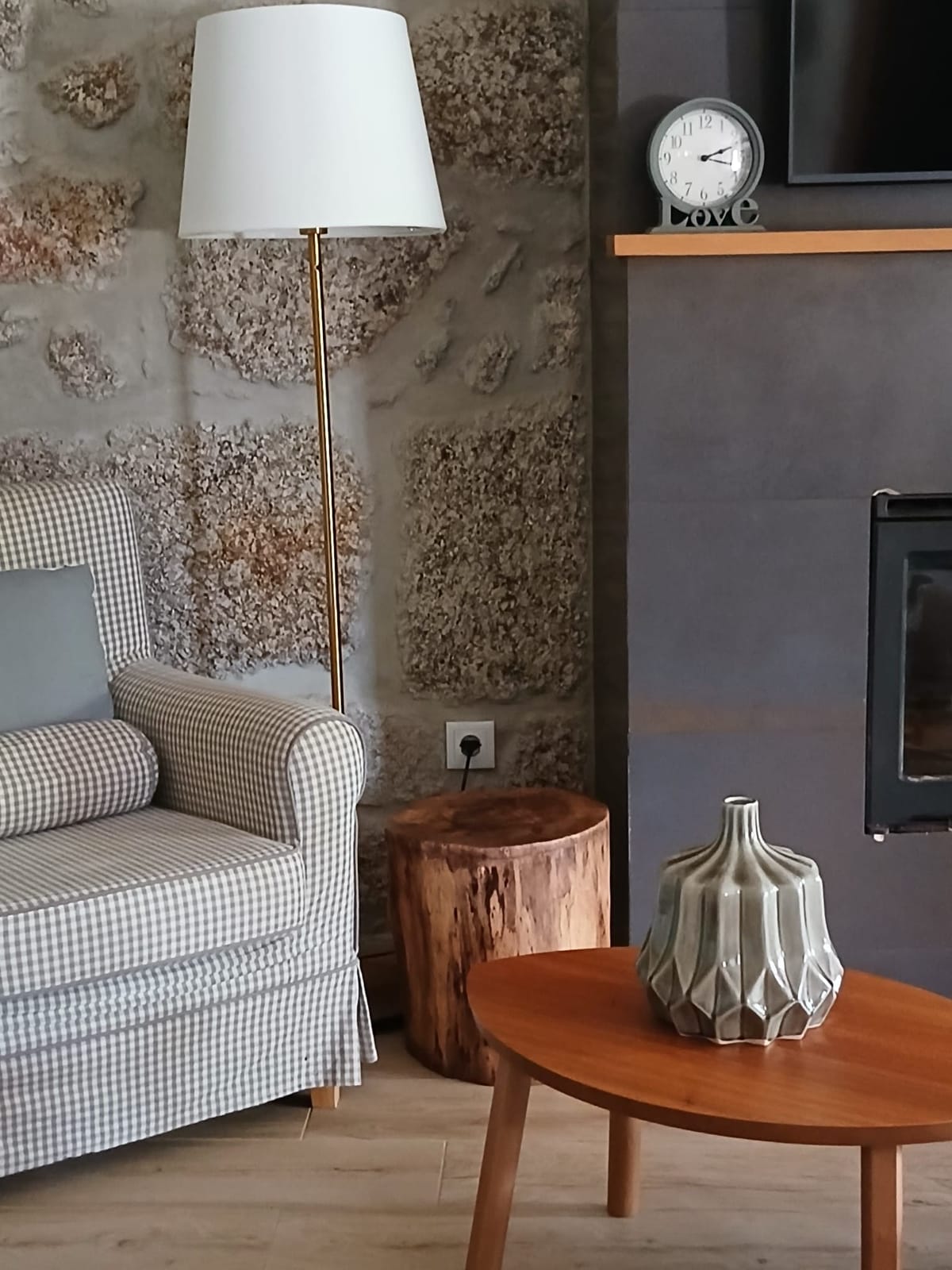 A sala, com a poltrona junto ao recuperador de calor e a parede de granito a vista.